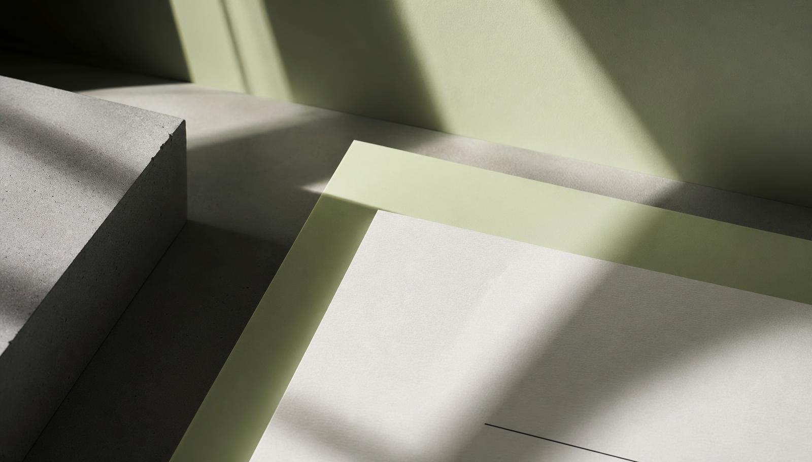 Minimalistische Architekturszene mit geschichtetem Papier, Beton und weichem grünem Licht
